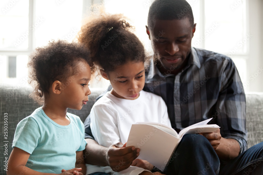 African American dad reading book to small kids African American dad reading book to small kids