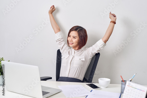 Satisfied woman relaxing with hands behind her head. Happy smiling employee after finish work, reading good news, break at work, girl doing simple exercise, relieve muscle stress, feeling well