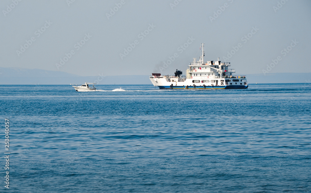 Large ship anchoring on Mediterranean sea with small motorboat on background on sunny day. Boat on the blue sea in summertime Large ship anchoring on Mediterranean sea with small motorboat on background on sunny day. Boat on the blue sea in summertime