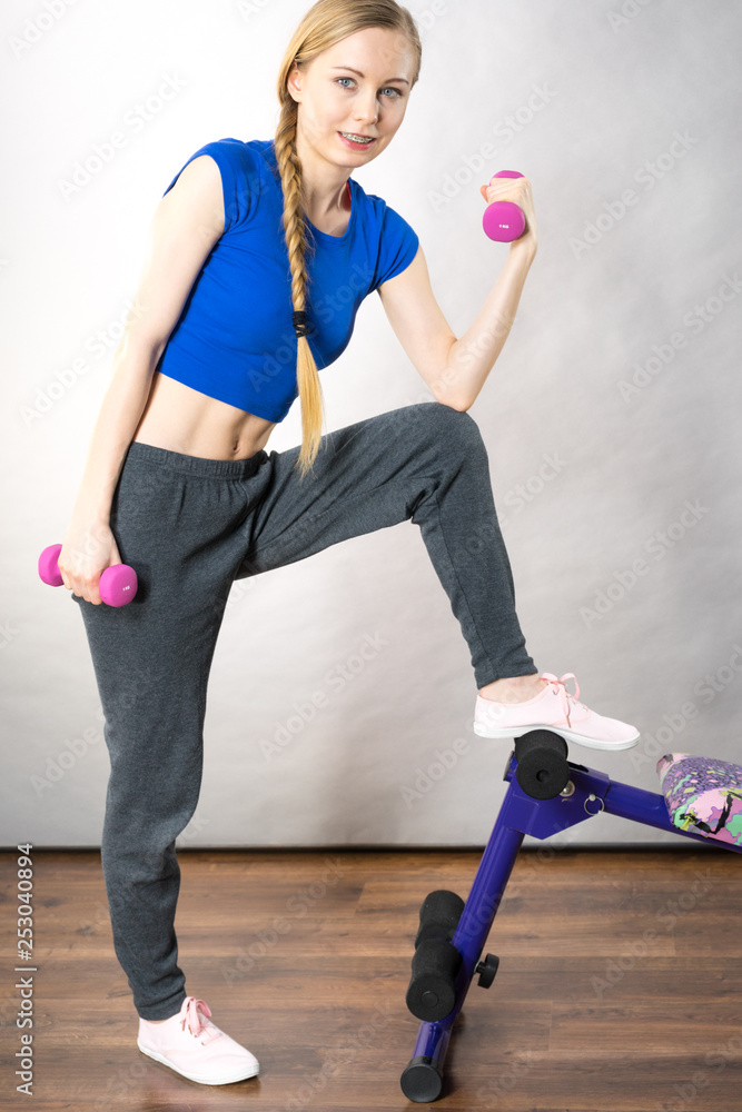 Obraz premium Teenage woman working out at home with dumbbell