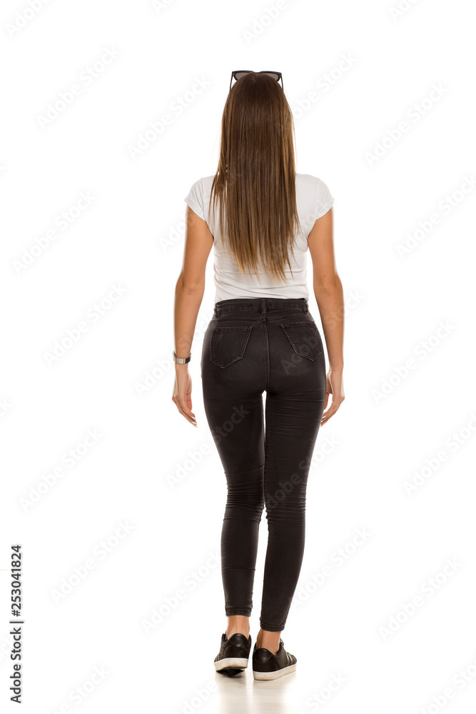 back view of young beautiful woman in black tight jeans posing on white  background Stock Photo | Adobe Stock