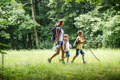 Konstfotografi Mother and her little sons hiking trough forest .