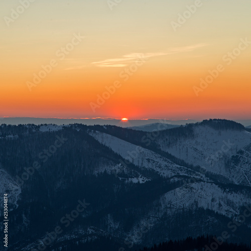 sunrise in the Carpathians on the background of blue mountain ranges and solar disk on the horizon.  © ihorhvozdetskiy