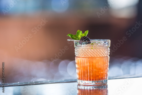 Cocktail drink bramble with black berries and mint at barcounter in night club or restaurant
