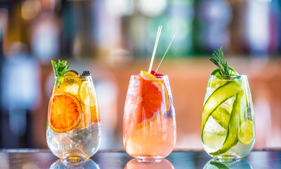 Tree colorful gin tonic cocktails in glasses on bar counter in pup or restaurant.