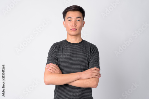 Portrait of young handsome Asian man with arms crossed
