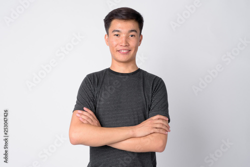 Portrait of young happy Asian man smiling with arms crossed