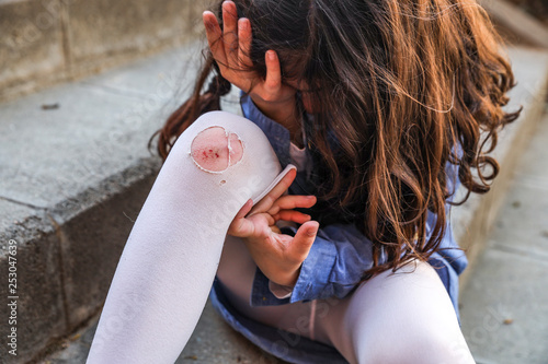 Little girl crying with a wound on her knee photo