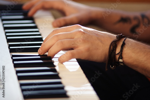 Beautiful male hands, on which bracelet and tattoo, play on musical modern synthesizer