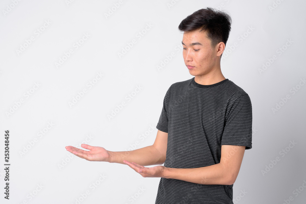 Portrait of young handsome Asian man showing something Portrait of young handsome Asian man showing something