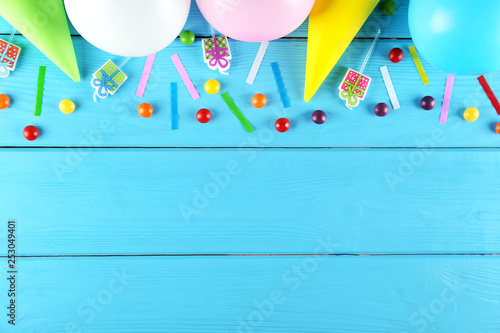 Minimal style composition with different pastel color air balloons with streamer ribbons and other chilldren birthday party attributes on bright background. Top view, close up, flat lay, copy space. photo