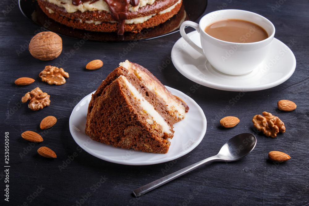Homemade chocolate cake with milk cream, caramel and almonds on black wooden background. cup of coffee. Homemade chocolate cake with milk cream, caramel and almonds on black wooden background. cup of coffee.