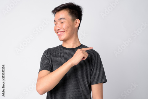 Portrait of young happy Asian man laughing and pointing finger