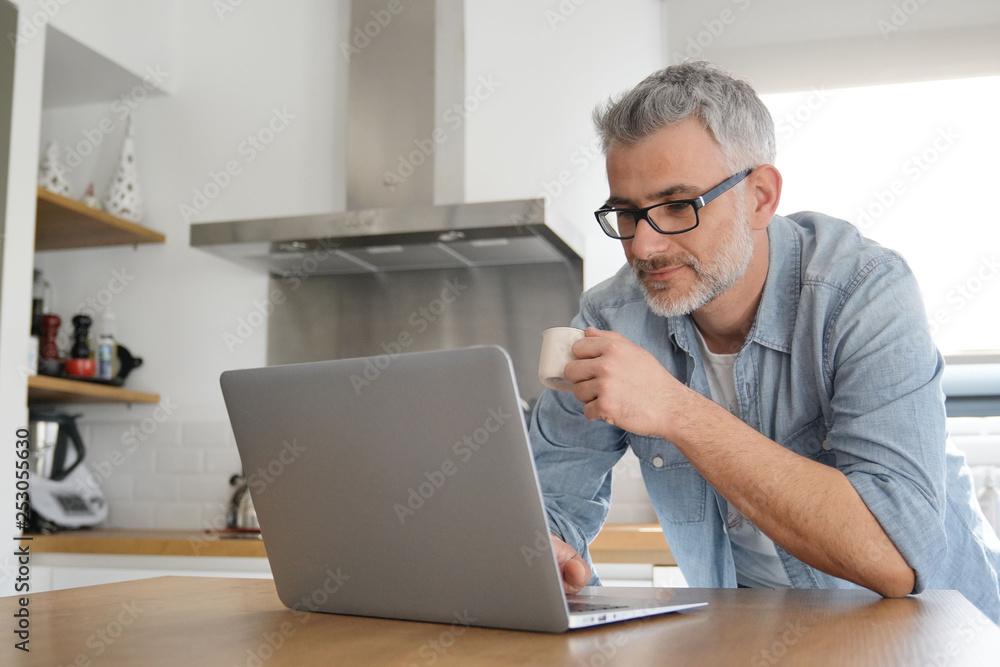 Man with computer at home in modern kitchen Man with computer at home in modern kitchen