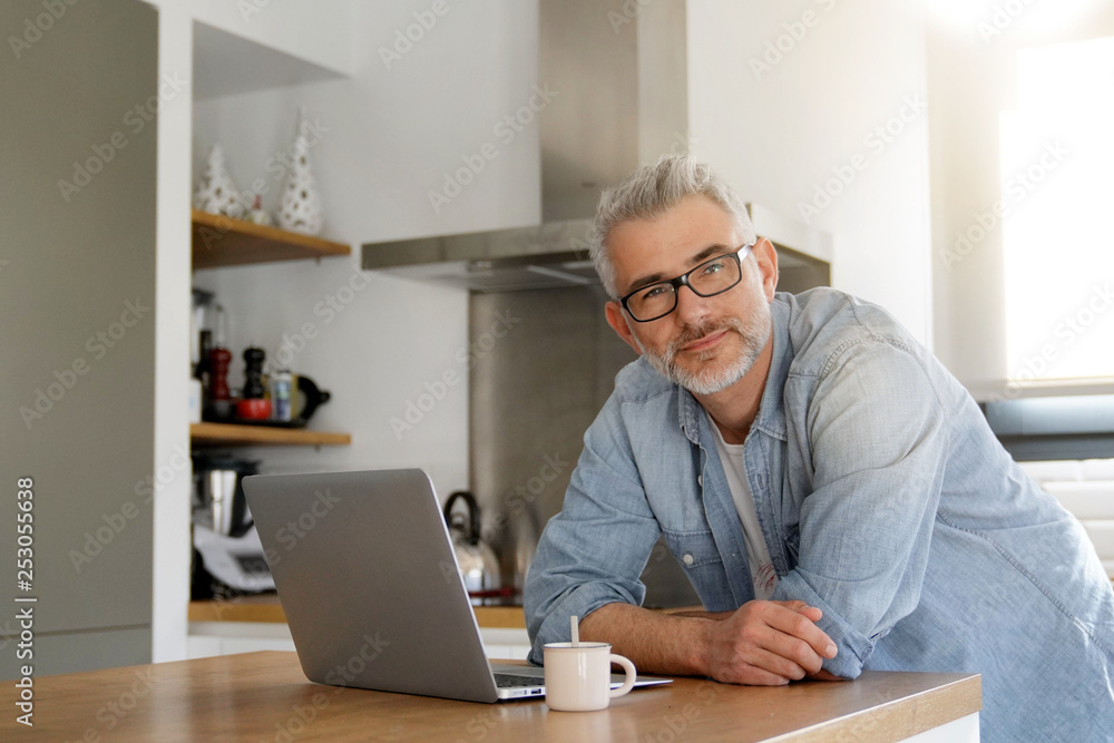 Man with computer at home in modern kitchen Man with computer at home in modern kitchen