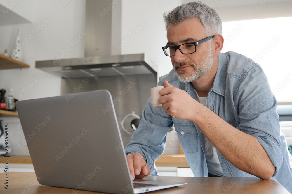Man with computer at home in modern kitchen Man with computer at home in modern kitchen