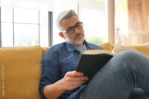 Man in 40s reading book in modern home photo