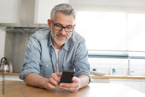 Man texting casually in kitchen at home photo