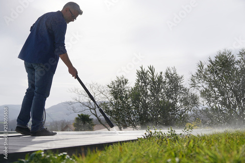 Man using high pressure washer on deck in garden