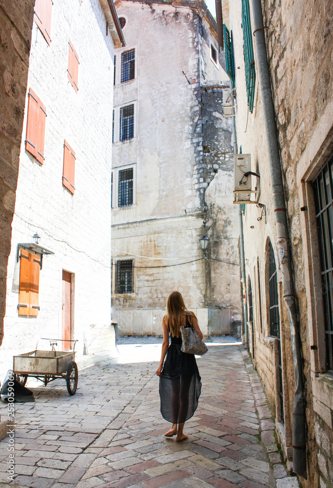 Girl walking down the street in the old town of Kotor, Montenegro, with its old stone houses and very narrow streets