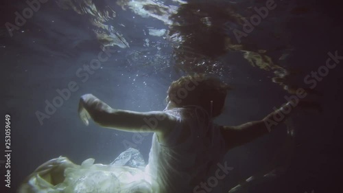 Girl in a white dress with ribbons under the water