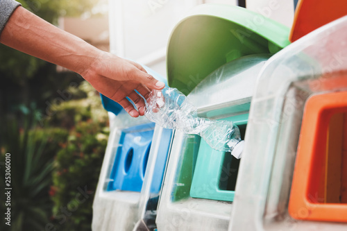 Canvas Print people putting plastic bottle in to recycle bin at park