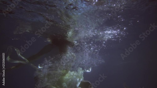 Girl in a white dress with ribbons under the water