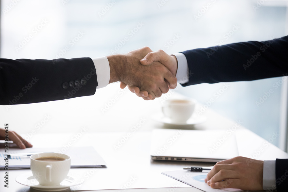 Businessmen in suits handshake after successful negotiation closing deal, closeup