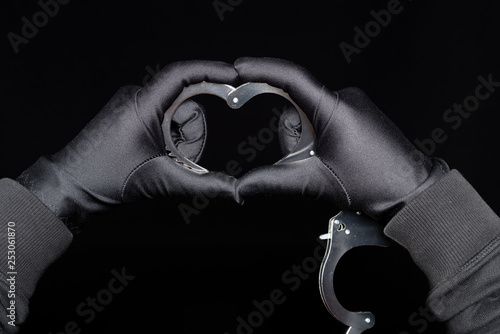 mens hands shaping the handcuffs like a heart on black