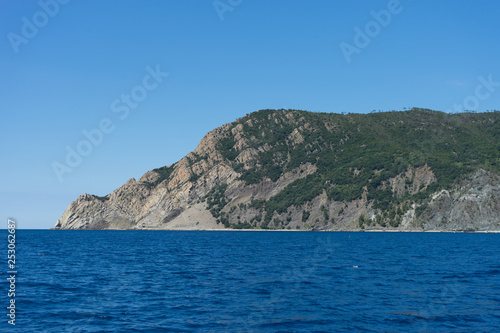 Italy, Cinque Terre, Monterosso, a large body of water with a mountain in the background © SkandaRamana