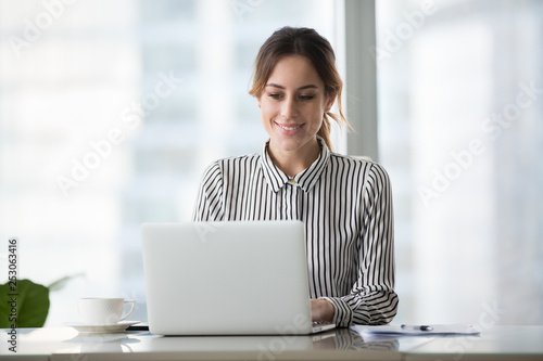 Happy businesswoman executive working online on laptop at office desk photo
