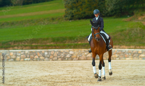 Carefree female English rider doing canter renvers at a dressage competition.