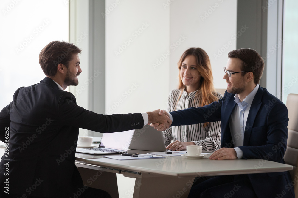 Business partners shaking hands negotiating at office meeting, collaboration concept Business partners shaking hands negotiating at office meeting, collaboration concept