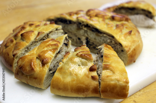 Chicken pie with rice and mushrooms, cut into pieces. Freshly baked kurnik on the table, traditional russian pie