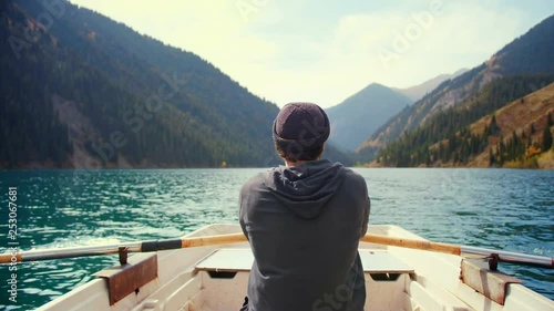 Hipster man is padding on the small boat or canoe in middle of lake and green pine woods forest mountains in nature of Asia in awaited active vacations holidays Feel calm relax desconection and sport