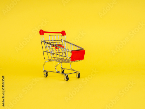 empty shopping cart on yellow background, copy space