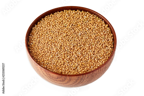 Organic yellow mustard seeds in wooden bowl isolated on white background