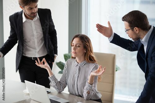 Slika na platnu Mindful calm woman boss meditating at work ignoring angry colleagues