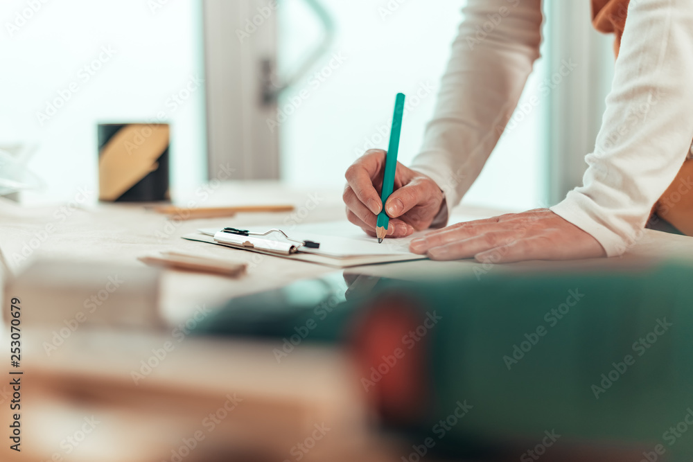 Self employed female carpenter writing project notes Self employed female carpenter writing project notes