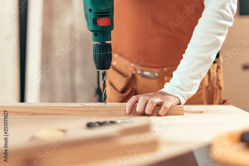 Female carpenter using electric drill