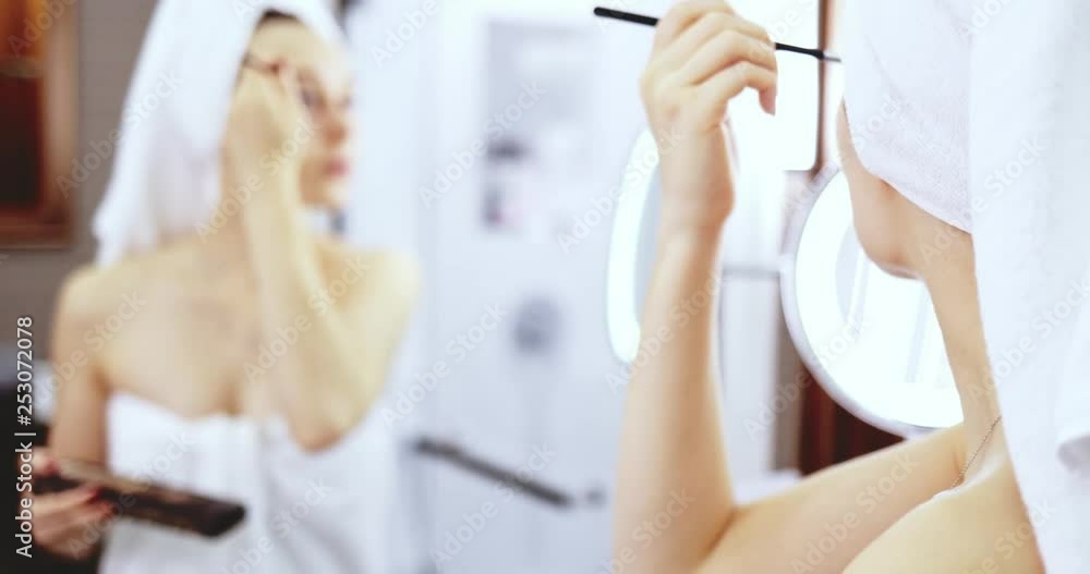 Young Woman Applying Make Up. SLOW MOTION. Girl apply nude eye shadow with brush, standing before the mirror in the bathroom after shower. Everyday beauty rituals. Young Woman Applying Make Up. SLOW MOTION. Girl apply nude eye shadow with brush, standing before the mirror in the bathroom after shower. Everyday beauty rituals.