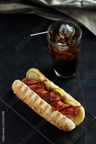 Hot dog with glass of coke on black background