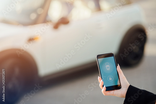 Woman using Smartphone near the car. Mobile phone apps for car owners concept.