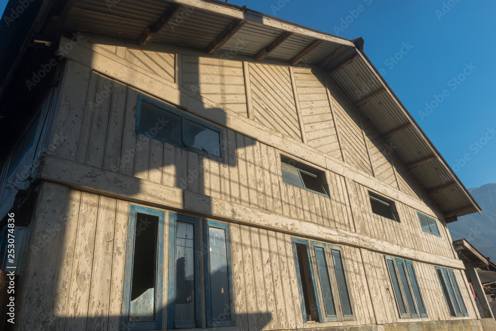 A wooden house or building early in the morning against a clear blue sky, with the sun throwing low shadows A wooden house or building early in the morning against a clear blue sky, with the sun throwing low shadows