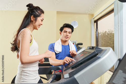 Woman training with instructor on treadmill