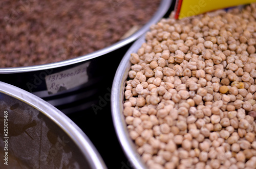 Lentils and white gram kept in steel containers in open for shopping in spice market in Old Delhi, India