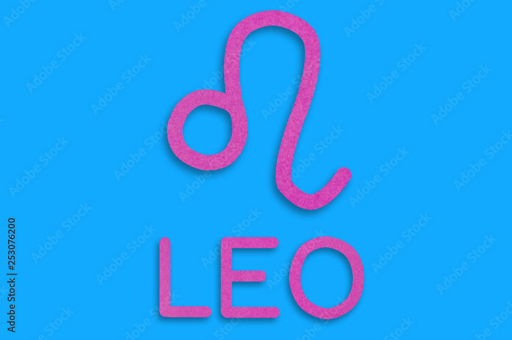 Fototapeta premium Symbol of astrological sign and word leo cut out of purple paper on blue table. Top view. Horoscope concept