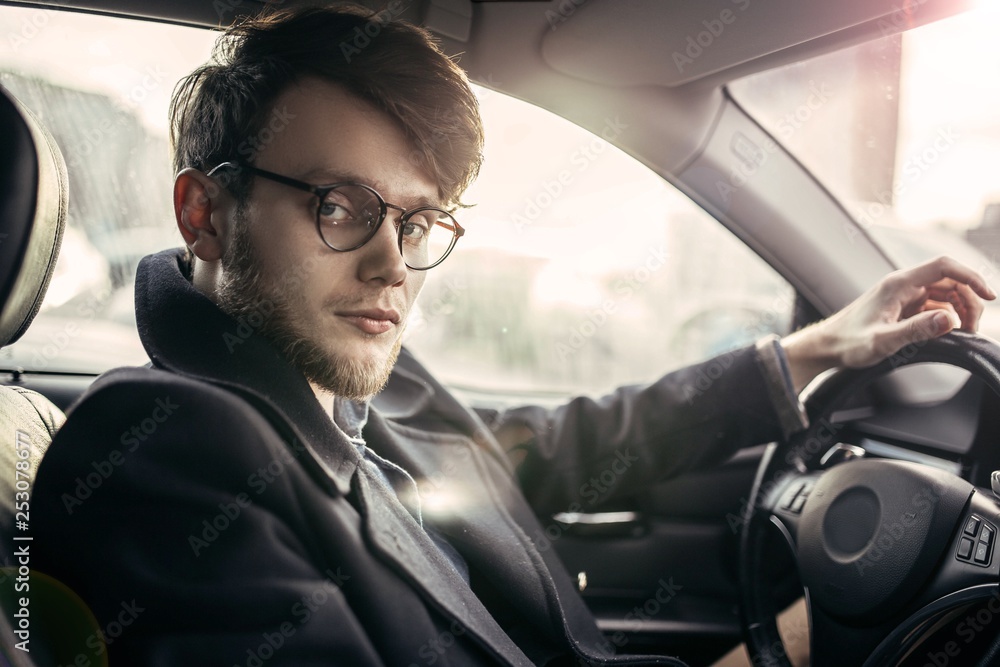 man hipster with a beard in glasses a driver of a modern car in salty weather. man hipster with a beard in glasses a driver of a modern car in salty weather.