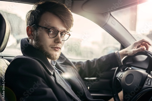 man hipster with a beard in glasses a driver of a modern car in salty weather. © velimir
