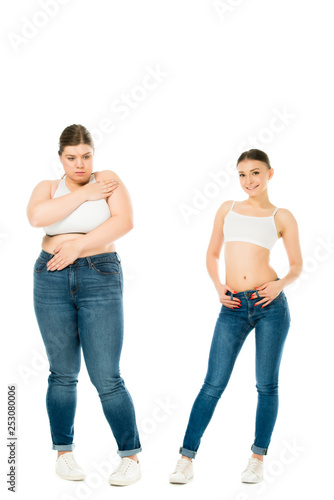 sad overweight woman covering body with hands while slim happy woman posing isolated on white